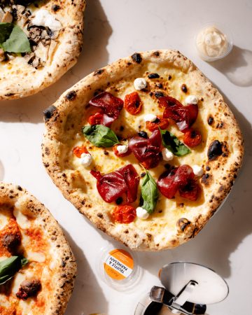 Rudy's Italian Pizza with Fior di latte, creamy lemon ricotta, bresaola and sweet confit tomatoes, finished with fresh lemon zest and basil.