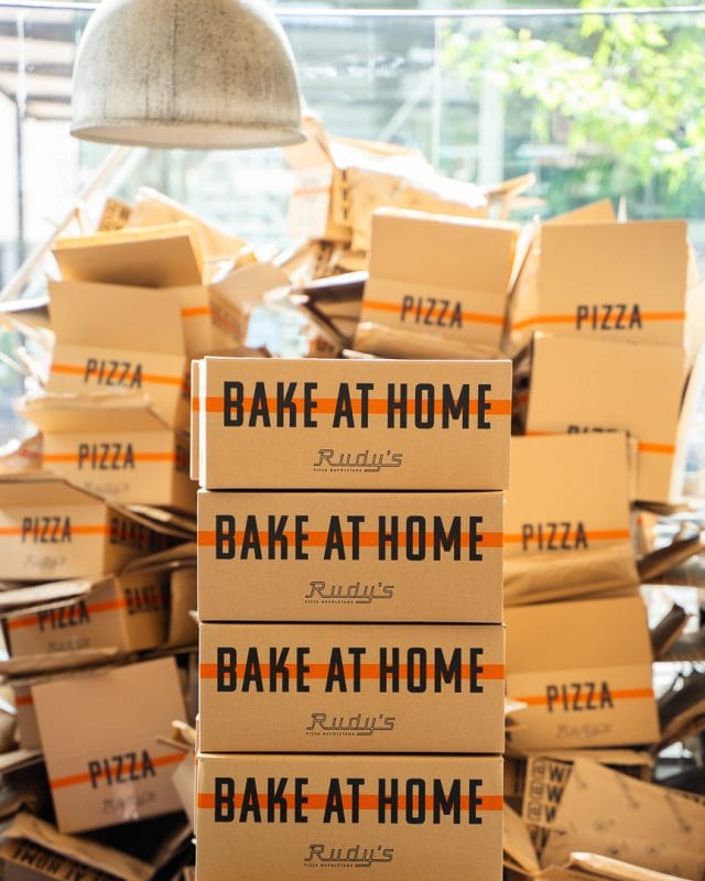pile of bake at home pizza boxes from rudy's
